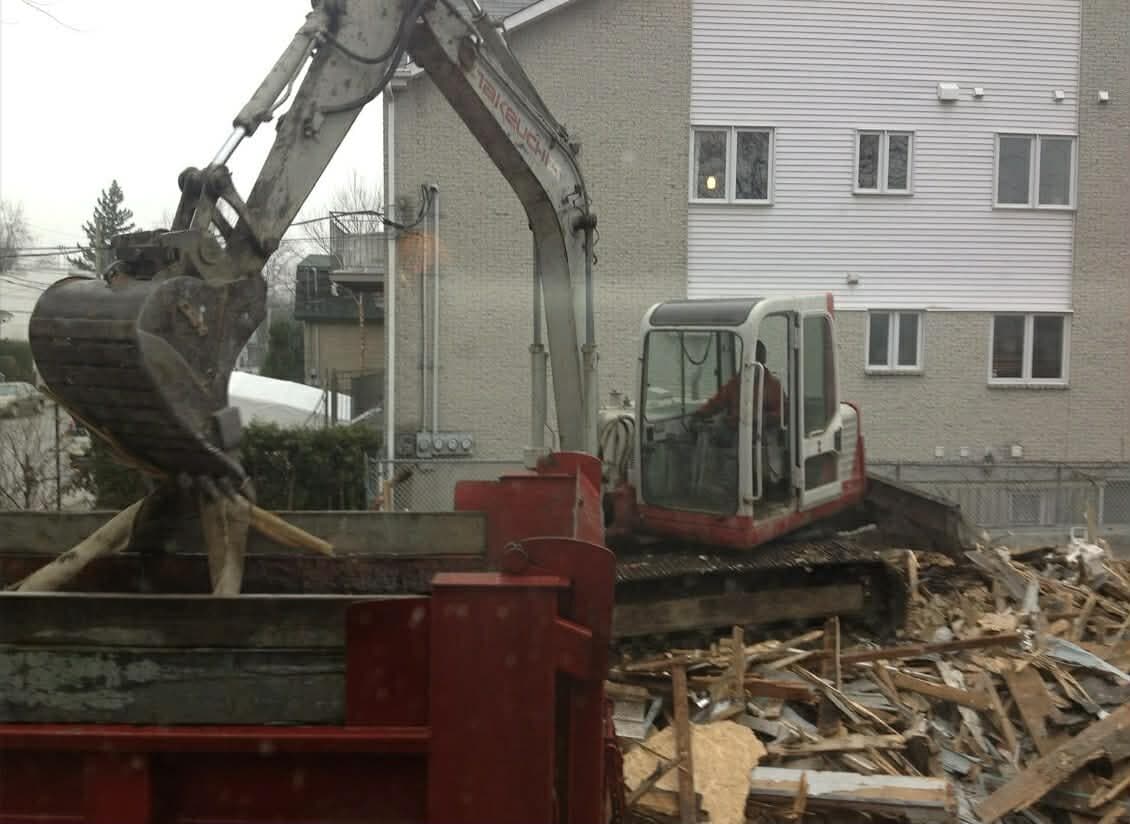 Excavator with grapple loading demolition debris