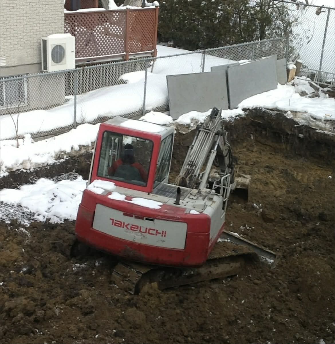 Takeuchi excavator digging on a residential lot