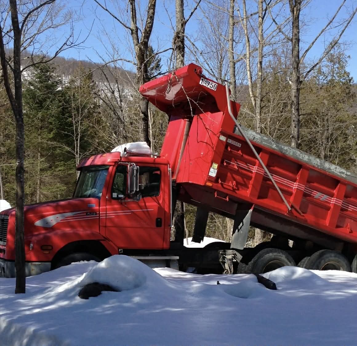 Red tandem dump truck with raised box in the Laurentians